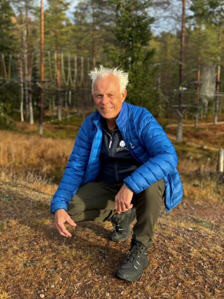 Naturturismföretagens generalsekreterare Johan Engström iklädd blå jacka sittande på huk framför en äventyrsbana.