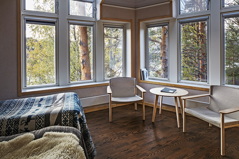 Interiör från Granö Beckasin. Tallstammar ses genom fönsterrutorna.